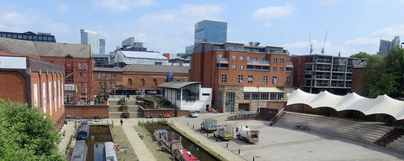 Narrowboats moored at Castlefield Basin in central Manchester, with the city centre behind